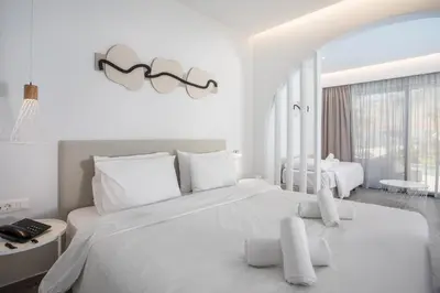 a white bedroom with a large bed with white pillows at Aiora Aqua Resort in Pefki Rhodes