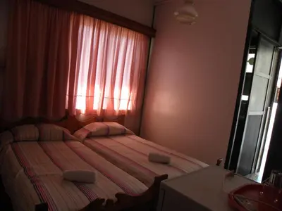 a small bedroom with two beds and a window at Afroditi Pension in Archangelos
