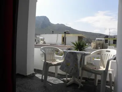 a table and chairs on a balcony with a table and a plant at Afroditi Pension in Archangelos