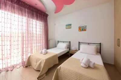 two beds in a room with pink curtains at Villa Elena in Triánta