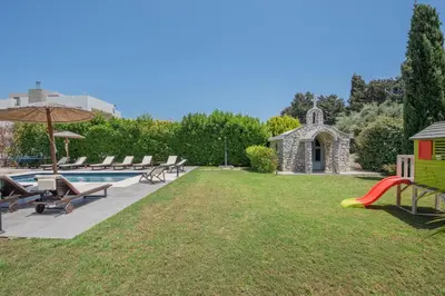 a backyard with a pool and chairs and an umbrella at Villa Elena in Triánta