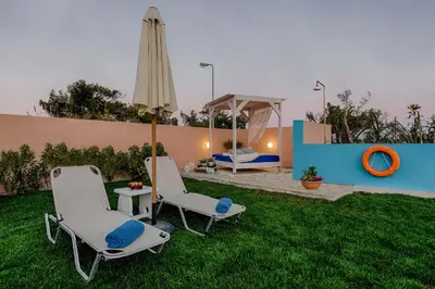a yard with two chairs and an umbrella at Afandou Beach Villas Sofias in Afantou