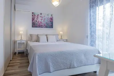 a white bedroom with a bed and a painting on the wall at Villa Dimitrios in Kiotari