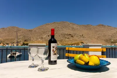 a bottle of wine and two glasses on a table at The Vegghera House in Symi