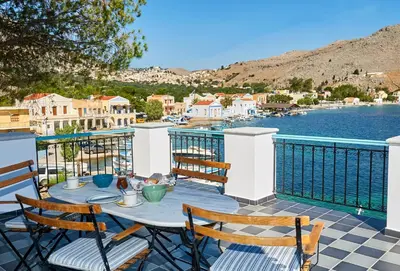 a table on a balcony with a view of the water at The Vegghera House in Symi