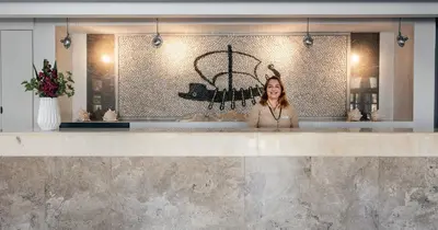 a woman standing behind a counter in a restaurant at Pedi Beach Hotel in Symi
