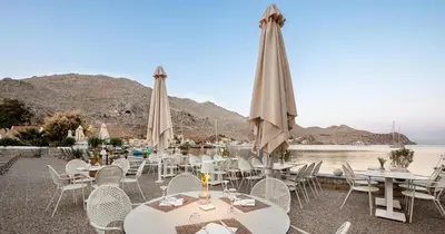 a group of tables and chairs with umbrellas at Pedi Beach Hotel in Symi