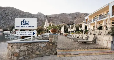 a row of chairs and umbrellas in front of a hotel at Pedi Beach Hotel in Symi