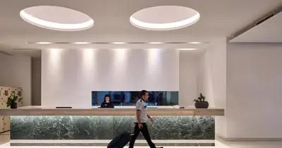 a man walking through an office lobby with luggage at Blue Sea Beach Resort in Faliraki