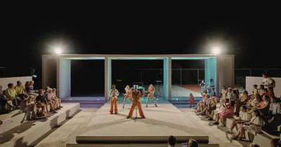 a group of people walking down a runway in front of a crowd at Blue Sea Beach Resort in Faliraki