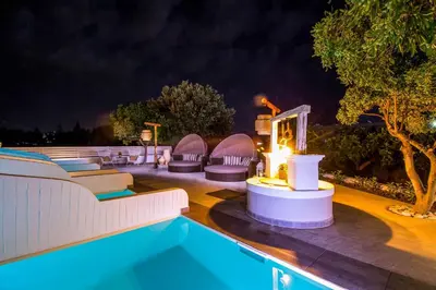 a pool at night with lounge chairs and a table at Malibu Boutique Studios & Bungalows in Faliraki