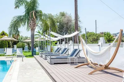 a group of chairs and hammocks next to a pool at Malibu Boutique Studios & Bungalows in Faliraki