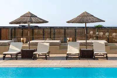 a group of chairs and umbrellas next to a pool at Blue Sky City Beach Hotel in Rhodes Town