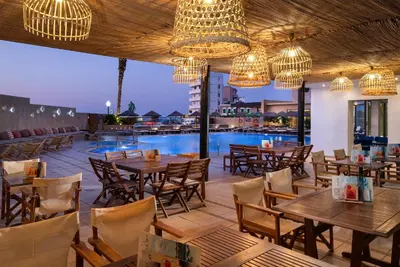 a restaurant with tables and chairs and a pool at Blue Sky City Beach Hotel in Rhodes Town