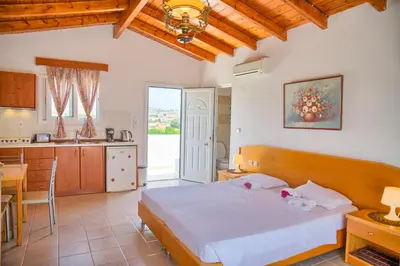 a bedroom with a large bed and a kitchen at Paul's Garden Studios in Haraki