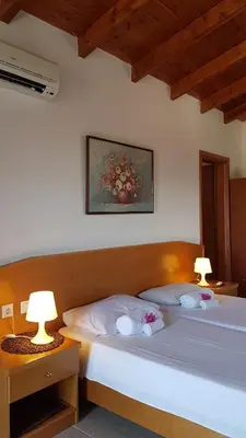 two beds in a room with two lamps on tables at Paul's Garden Studios in Haraki
