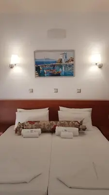 a large white bed with three pillows on it at Paul's Garden Studios in Haraki