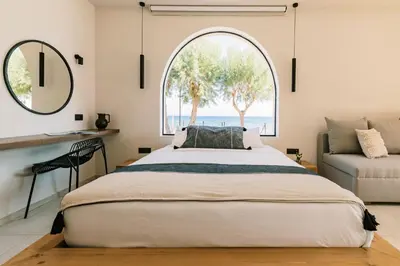 a bedroom with a large bed and an arched window at Villa Di Mare Seaside Suites in Ixia