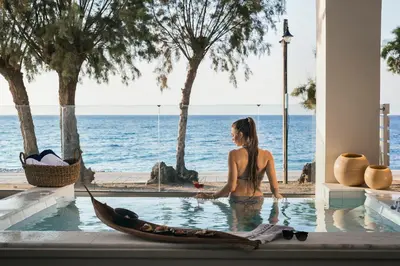 a woman sitting in a swimming pool next to a boat at Villa Di Mare Seaside Suites in Ixia