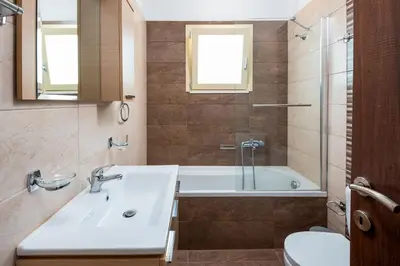 a bathroom with a sink and a tub and a toilet at Kolymbia Village in Kolimbia