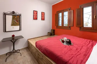 a bedroom with a bed with red sheets and a table at Villa Anastasia in Líndos