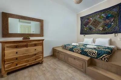 a bedroom with a bed with a dresser and a mirror at Villa Eleni with Hot Tub and Acropolis View in Líndos