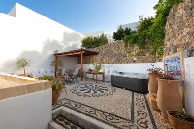 a patio with a hot tub and a table and chairs at Villa Eleni with Hot Tub and Acropolis View in Líndos