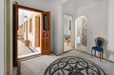 a hallway with a blue chair and a door at Villa Eleni with Hot Tub and Acropolis View in Líndos