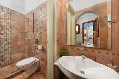 a bathroom with a sink and a toilet and a mirror at Villa Eleni with Hot Tub and Acropolis View in Líndos