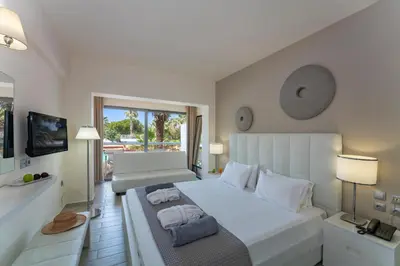 a bedroom with a large white bed and a television at All Senses Ocean Blue Sea Side Resort - All Inclusive in Kremasti