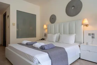 a bedroom with a large white bed with towels on it at All Senses Ocean Blue Sea Side Resort - All Inclusive in Kremasti