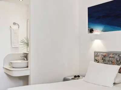 a white bathroom with a sink and a bed at Esperia City Hotel in Rhodes Town