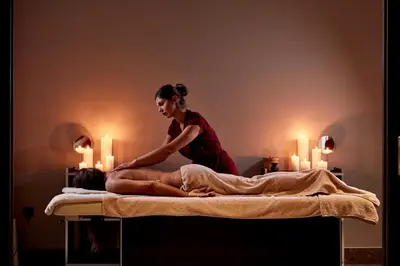 a woman sitting on top of a bed with a woman getting a massage at Esperos Village Blue & Spa - Adults Only in Faliraki