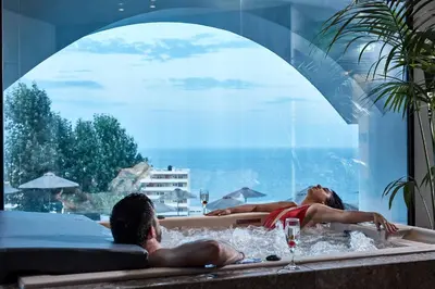 a woman laying in a bath tub with a man at Esperos Village Blue & Spa - Adults Only in Faliraki