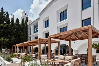 an outdoor patio with tables and chairs in front of a building at Esperos Village Blue & Spa - Adults Only in Faliraki
