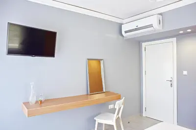 a room with a tv on a wall with a chair at Alkyoni City Apartment in Rhodes Town