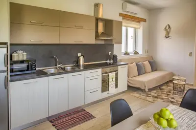 a kitchen with white cabinets and a table and a couch at G&K Stone Suites in Haraki