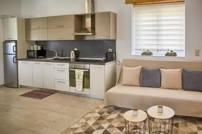 a living room with a couch and a kitchen at G&K Stone Suites in Haraki