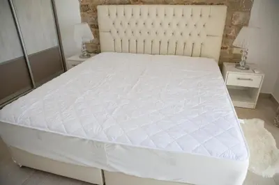 a white bed in a bedroom with two night stands at G&K Stone Suites in Haraki
