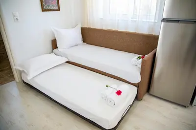 two beds in a room with a refrigerator at Haraki Stone Apartments in Haraki