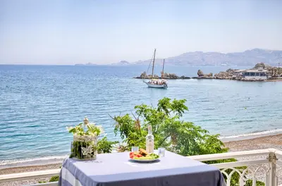 a table with a plate of food and a boat in the water at Chara's Sea View House in Haraki