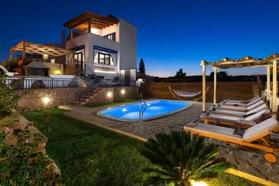 a villa with a swimming pool in front of a house at Villa Rose on the beach in Afantou