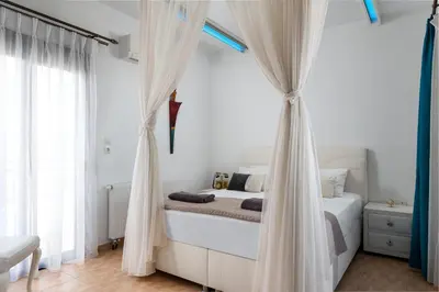 a bedroom with a bed with white curtains at Villa Rose on the beach in Afantou