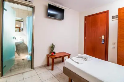 a bathroom with a bed and a shower and a television at Filmar Hotel, Ixia, Rhodes in Ixia