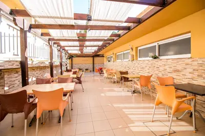 a cafeteria with tables and chairs and a brick wall at Filmar Hotel, Ixia, Rhodes in Ixia