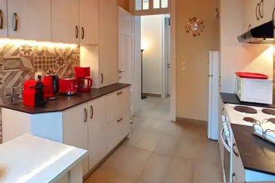 a kitchen with white cabinets and red appliances at Italian flair with a view in Rhodes Town