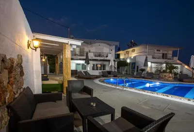 a villa with a swimming pool at night at Toulas Studios & Apts No2 in Faliraki