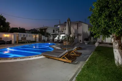 a swimming pool with lounge chairs and an umbrella at Toulas Studios & Apts No2 in Faliraki