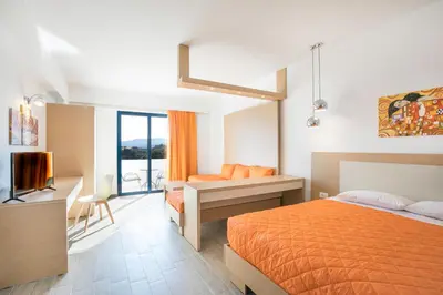 a bedroom with a bed and a desk and a television at Ekaterini Hotel in Kiotari