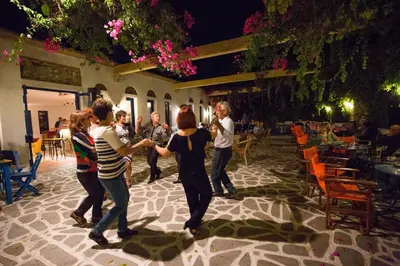 a group of people dancing in a courtyard at night at Ekaterini Hotel in Kiotari